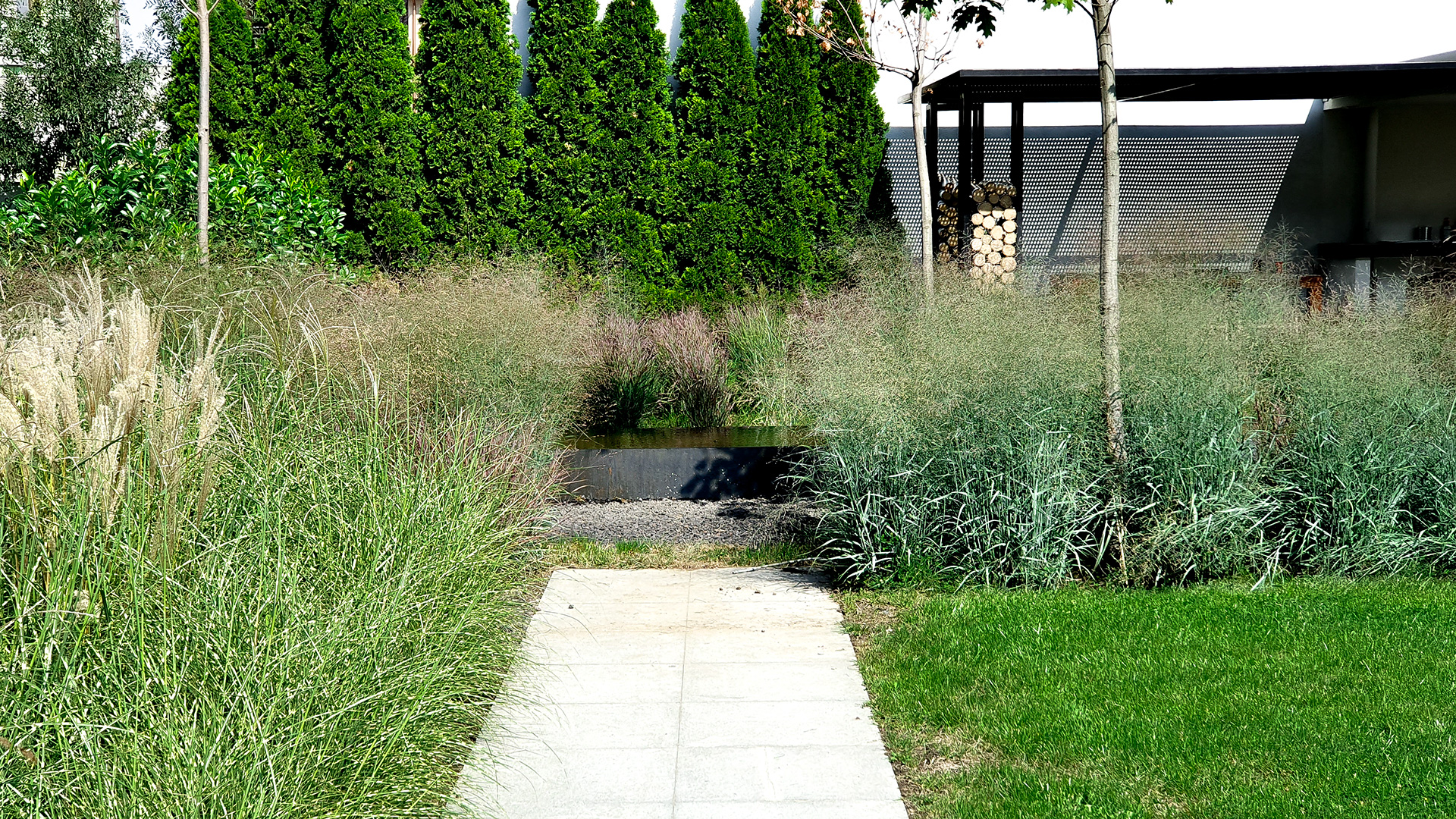 Alee din piatră care duce spre un bazin decorativ cu apă și ierburi ornamentale