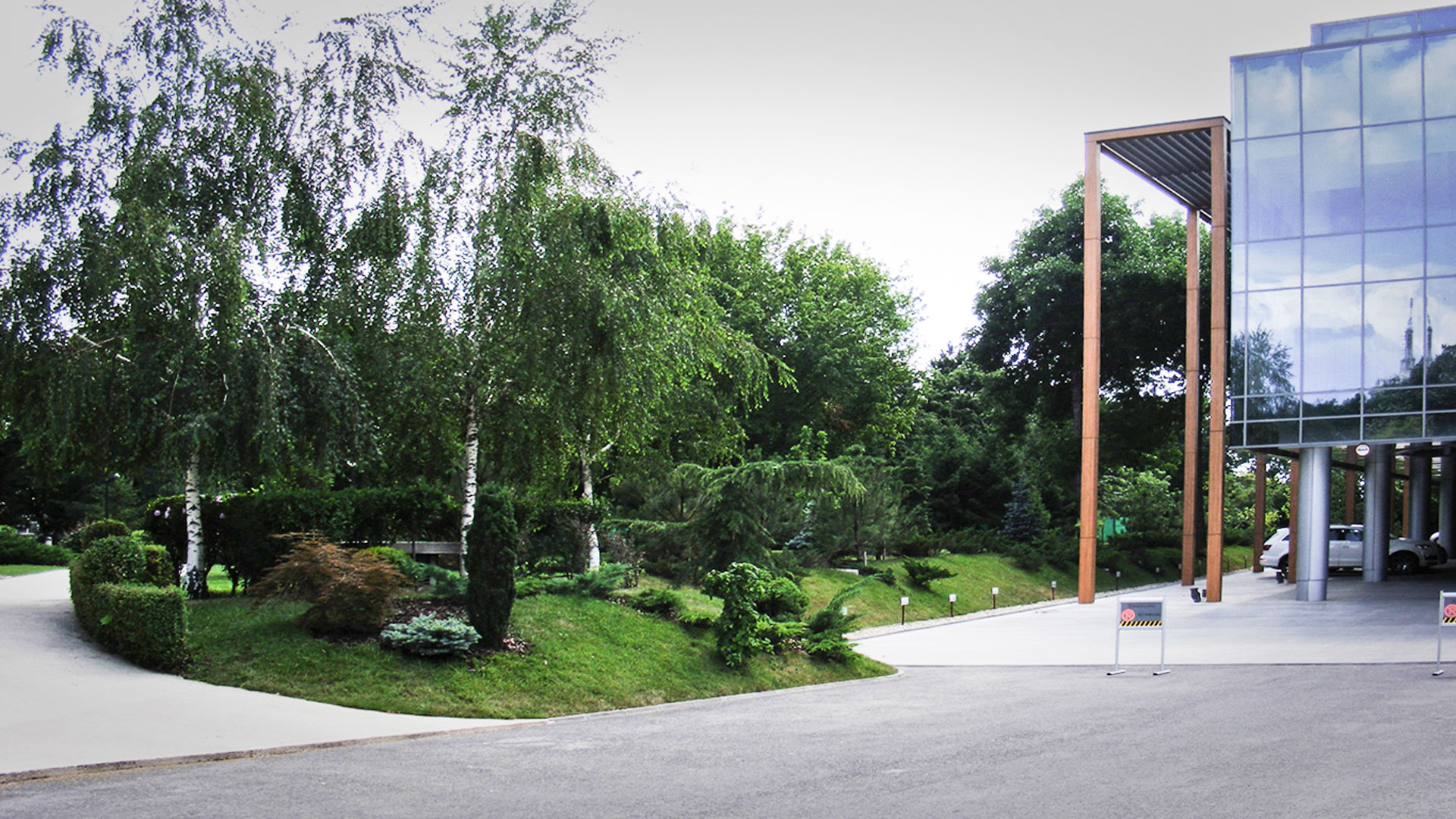 Taluz plantat cu arbuști și arbori care separă grădina Crowne Plaza de clădirea Ana Group