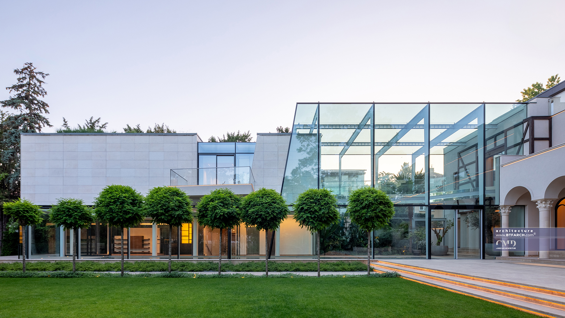 Sera din sticlă integrată într-o grădină clasică cu vegetație luxuriantă