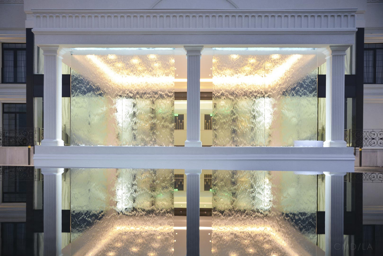 Perete de apă cu efect de cascadă, reflectat într-un bazin, în fața unuia dintre pavilioanele elegante Ramatuelle.