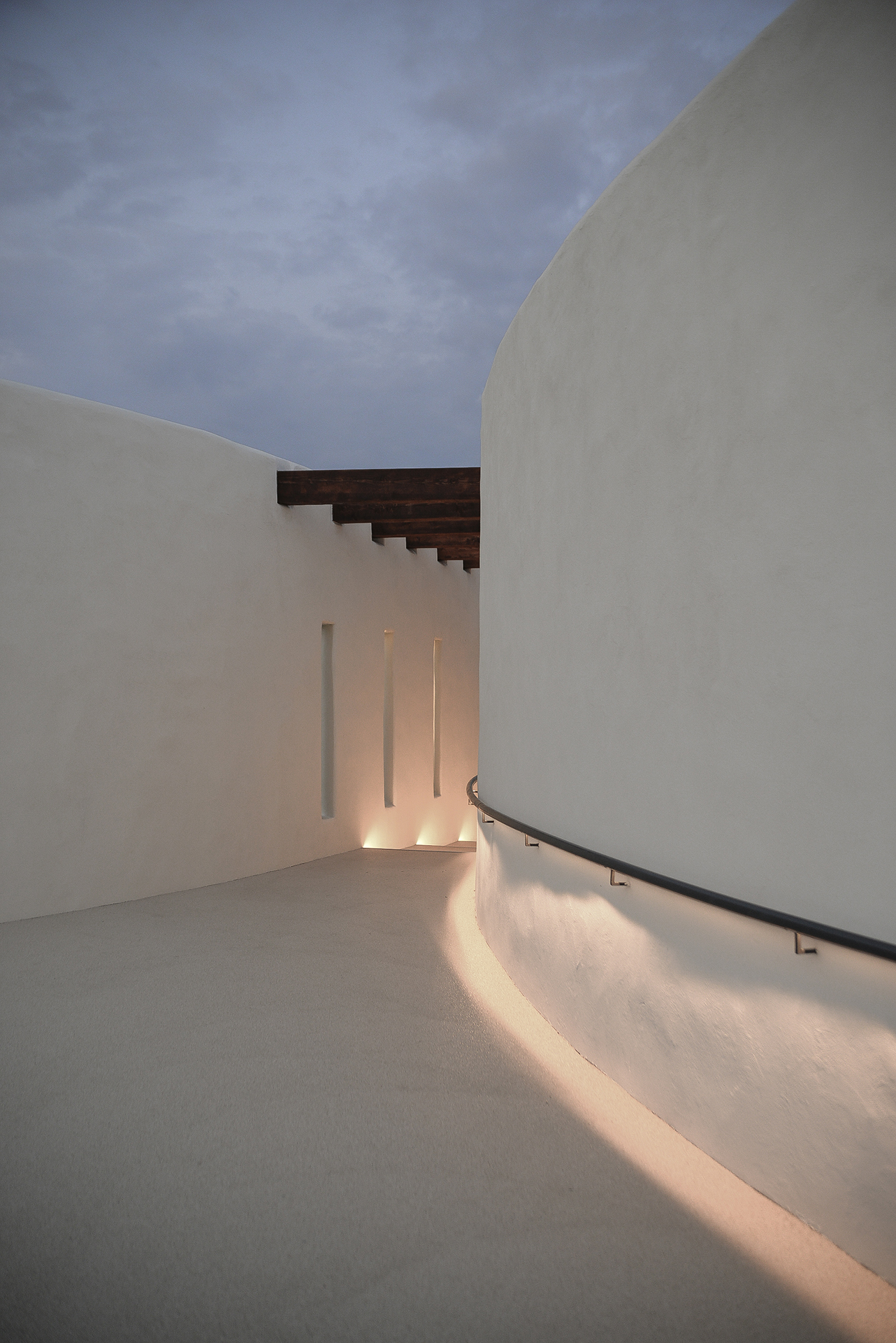 Pasaj arhitectural curbat cu pereți albi și iluminat ambiental – detaliu spațiu de tranziție Ramatuelle